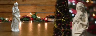 Figura de la Virgen con el Niño Jesús delante de luces de Navidad desenfocadas