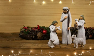 Belén blanco con Sagrada Familia y animales sobre mesa de madera y adornos de Navidad